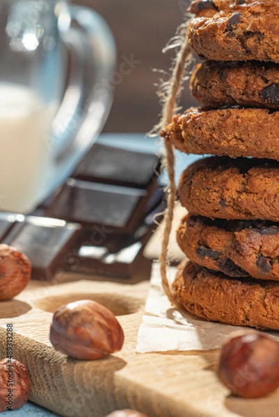 Fototapeta Homemade cookies with raisins, chocolate, nuts and milk on a wooden table and a art phone. Breakfast. Close up.