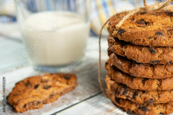 Fototapeta Homemade cookies with raisins, chocolate, nuts and milk on a wooden table and a art phone. Breakfast. Close up.