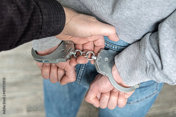 Fototapeta A criminal has been detained. Hands are wound back, handcuffs are put on to prevent aggression.