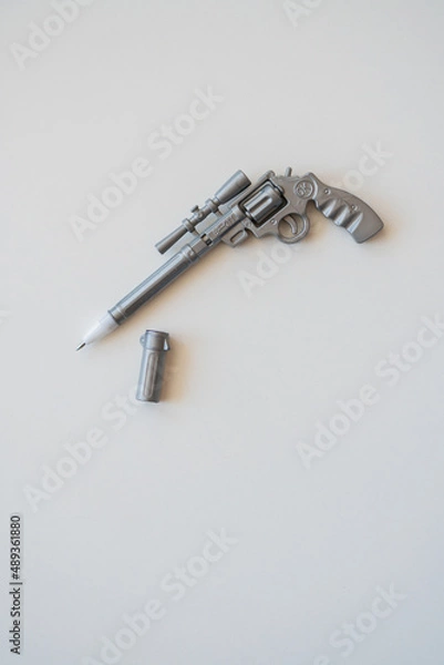 Fototapeta a pen in the form of a pistol lies on a table on a white background.