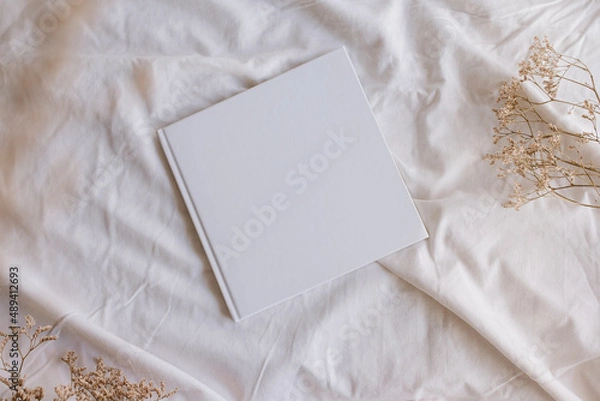 Obraz White book mockup with some dry sheets on the bed.