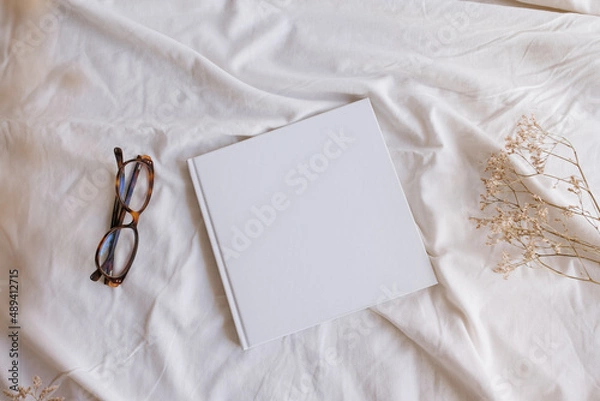 Obraz White book mockup with some glasses and dry sheets on the bed.