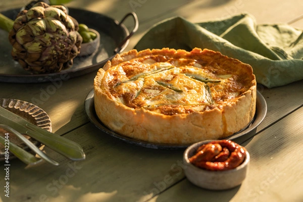 Fototapeta Golden organic healthy crispy pie with artichokes, dried tomatoes and olives on the table