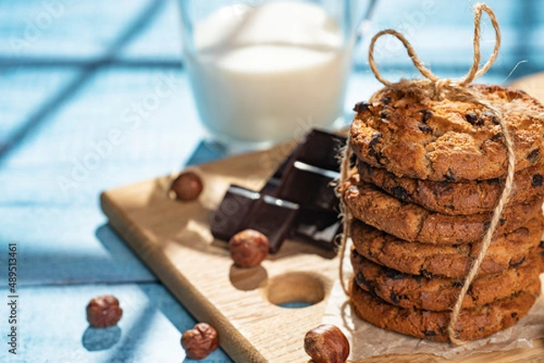 Fototapeta Homemade cookies with raisins, chocolate, nuts and milk on a wooden table and a art phone. Breakfast. Close up.