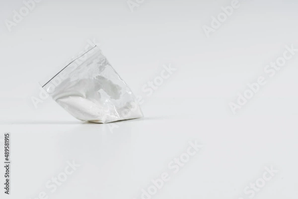 Fototapeta Cocaine in a plastic bag on a white background with copy space.