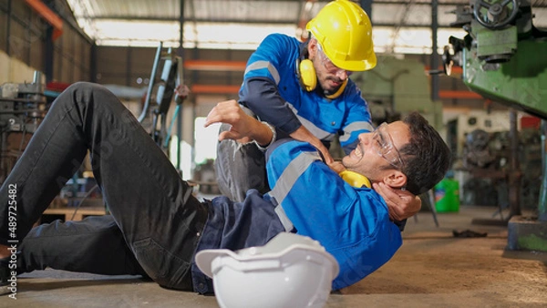Obraz Man labor worker had accident on the floor at the production line of CNC machine factory. Engineer man walk to that area and support him on injured. Safety in industrial factory. Injury at work..