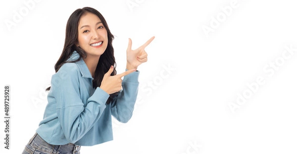 Fototapeta Beautiful young Asian woman pointing up to copy space and looking at camera with smile face and happy Pretty girl act like a satisfied product, use for advertising with isolated on white background
