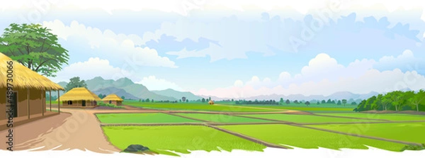 Fototapeta A view of a peaceful village. Large farmlands in the middle of a large landscape. Village houses with rice and paddy fields.