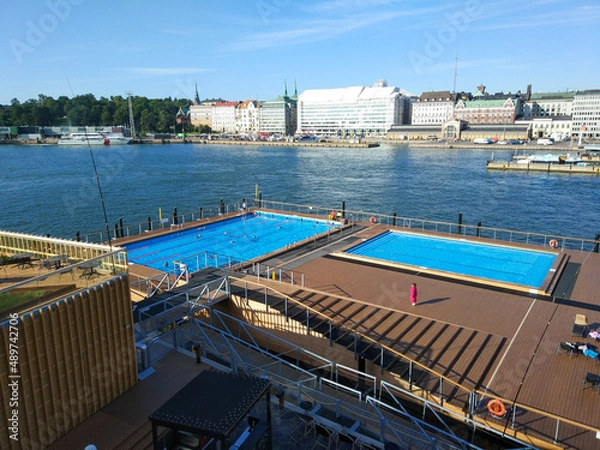 Fototapeta Helsinki, Finland - August 29, 2017: People bathe in an open public pool against the backdrop of the seaport and city buildings.