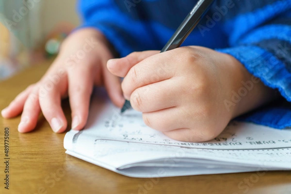 Obraz 学習プリント。算数の宿題に取り組む小学生の男の子。左利き