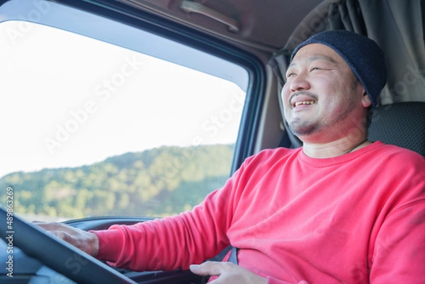 Obraz 大型トラックを運転している笑顔の男性ドライバー