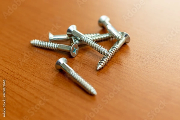 Obraz 木の机の上の金属ネジ