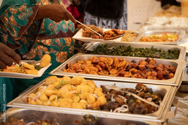 Obraz Close-up of African food during a buffet at a party. Fried plantains, potatoes, meat and vegetables