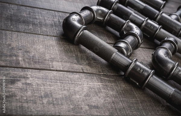 Obraz Cast iron pipes and fittings of different shape and forms, laying on a rustic wooden table