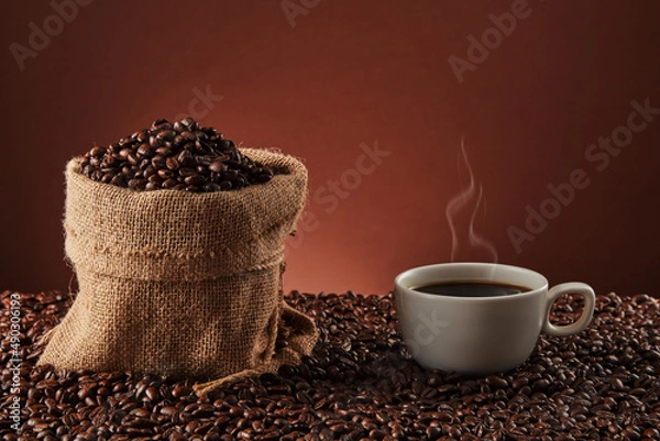 Fototapeta White cup with coffee beans on dark background