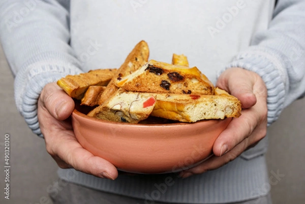 Fototapeta A middle age man holds a plate with homemade cookies with raisins, chocolate, nuts. Breakfast. Close.