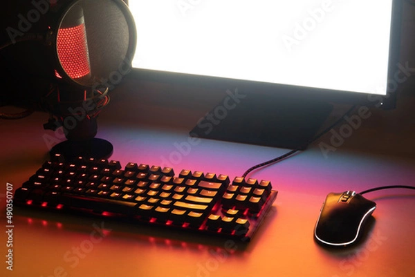 Fototapeta gaming workspace for streamer. gaming set up with a gaming keyboard, a gaming mouse, a luminous microphone and a white screen	