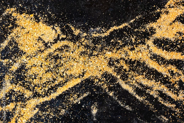 Fototapeta Small bread crumb on black. Gold dust on a black background. Small particles of gold rock on black.