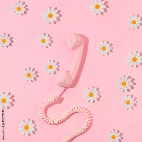 Fototapeta Spring creative layout with pink retro phone handset and white flowers on pastel pink. 80s or 90s retro fashion aesthetic telephone and flowers concept. Minimal romantic communication idea.