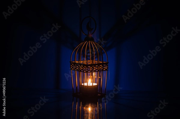 Fototapeta Black lantern with reflection from blue background for the Muslim feast of the holy month of Ramadan Kareem.