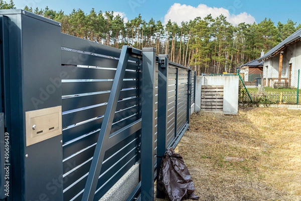 Fototapeta Modern anthracite panel fence, visible sliding gate to the garage, view from the garden.