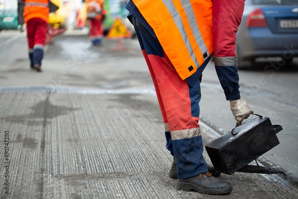 Fototapeta A worker pours liquid asphalt, molten bitumen from a bucket of resin.