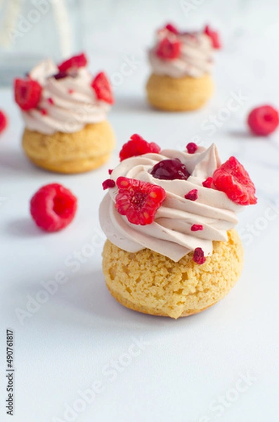 Obraz mini eclairs with cream and fresh raspberries on a light background