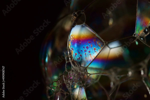 Fototapeta Sunlight refracting through a soap bubble and reflecting a spectrum of colours from the inside surface. Selective focus.