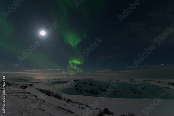 Fototapeta In winter, the moon and the aurora borealis are in the sky.