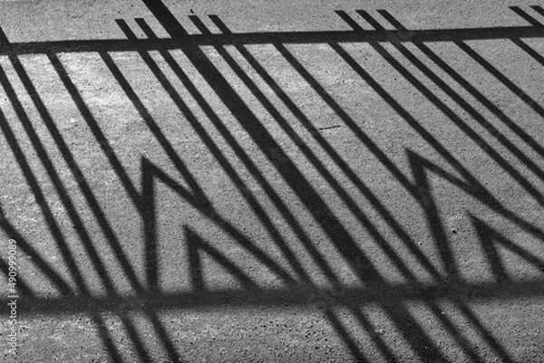 Fototapeta Geometric pattern fence shadow on sidewalk