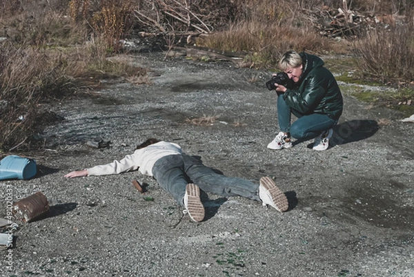 Obraz a female forensic expert photographs the body of a dead homeless girl who died in a car accident on