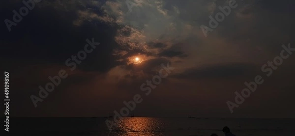 Obraz Hidden sun in dark cloud over sea