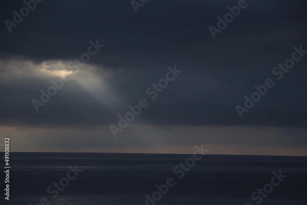 Fototapeta Ray light between the clouds over the ocean