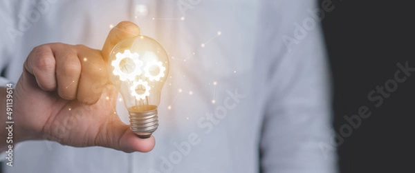 Fototapeta Hand of a man holding an illuminated light bulb.Idea innovation and inspiration concept.
