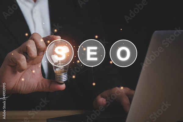 Fototapeta SEO Search Engine Optimization concept businessman holding lighting bulb for the idea to working.