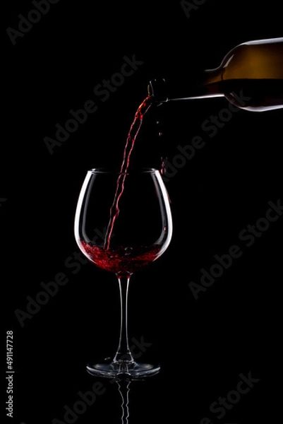 Fototapeta Still life with a glass of red wine and a bottle on a black background