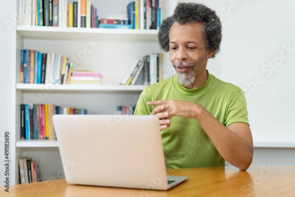 Fototapeta Old african american man watching webinar online
