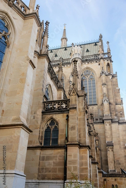 Fototapeta Linz, Austria, 27 August 2021: Facade of medieval catholic stone gothic New Cathedral of Immaculate Conception with arch, old town street at sunny summer day, lancet windows and carved statues