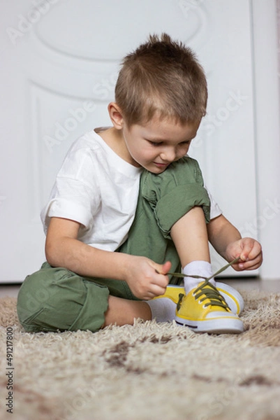 Obraz a small child ties his shoelaces