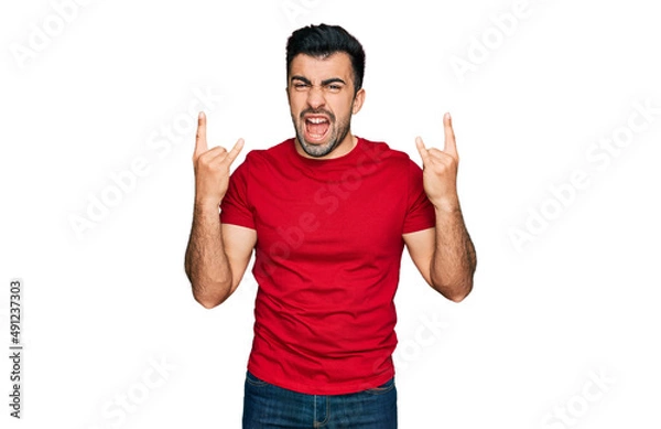 Fototapeta Hispanic man with beard wearing casual red t shirt shouting with crazy expression doing rock symbol with hands up. music star. heavy concept.
