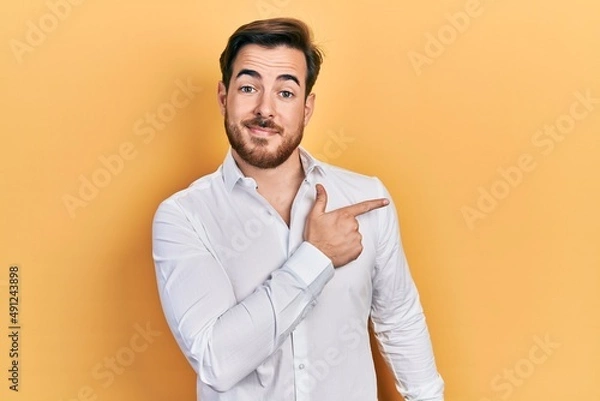 Fototapeta Handsome caucasian man with beard wearing business white shirt smiling cheerful pointing with hand and finger up to the side