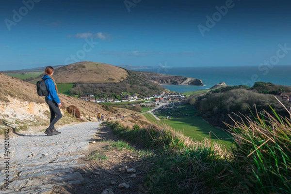 Fototapeta Girl in blue hoodie and with the black backpack looks on the Lulworth Cove, Jurassic Coast, Dorset, UK