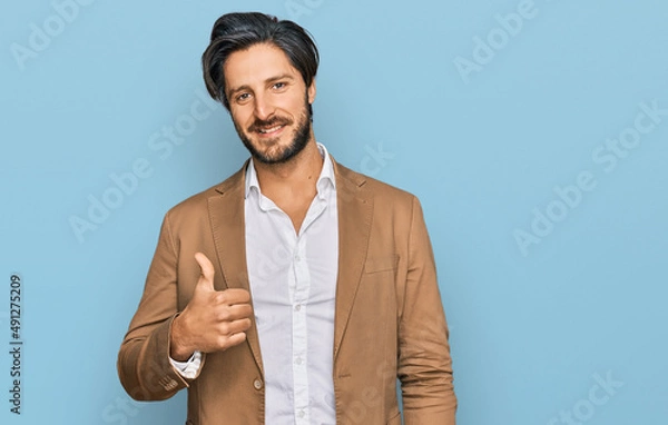 Fototapeta Young hispanic man wearing business clothes doing happy thumbs up gesture with hand. approving expression looking at the camera showing success.