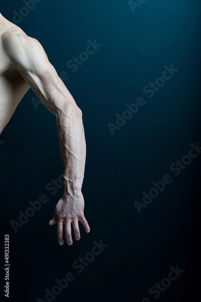 Obraz Strong hand of faceless male with arm stretching on dark background.