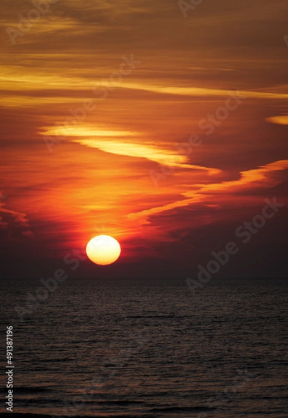 Obraz sun setting in the sea with cloud trails