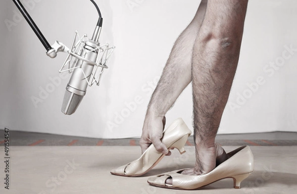 Fototapeta Foley woman steps with caucassian man hands inside femail shoes front a silver studio mic over a wood table