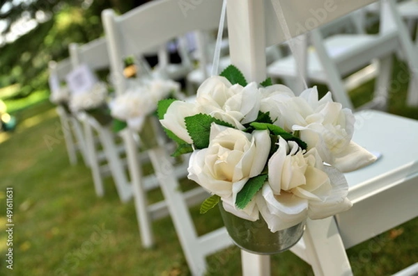 Fototapeta White Chairs Adorned with White Fabric Rose Bouquets Await Guests at a Garden Wedding