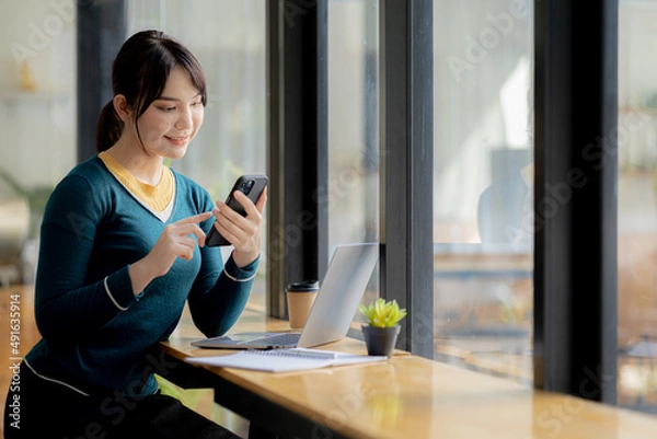Fototapeta Woman is pressing a mobile phone to send an online message to her classmates, she is a university student studying online due to the COVID-19 pandemic. Online learning to reduce the epidemic concept.