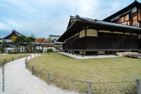 Fototapeta view of curved path outside an ancient japanese religious building. picture of pathway winding along the lawn in front of a zen buddhist temple.