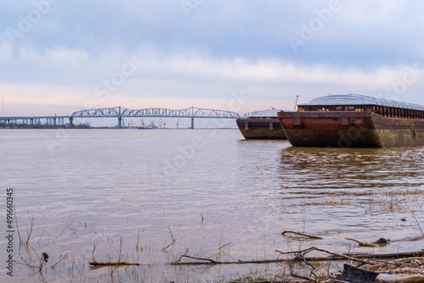 Fototapeta Two barges docked on the Mississippi River with the Huey P. Long Bridge in the background on March 3, 2020 in Jefferson, LA, USA